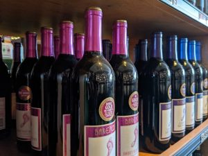 Many bottles of wine are lined up on a shelf.