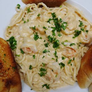 A plate of pasta with shrimp and bread.